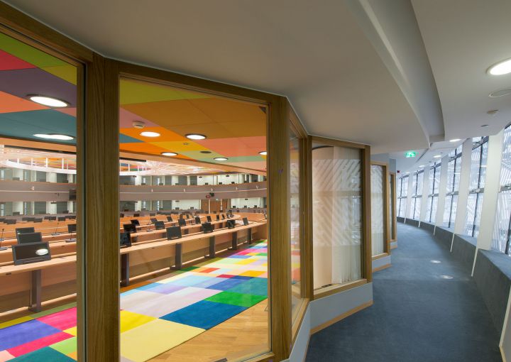Houten raamkaders met zicht op vergaderzaal met gekleurd tapijt